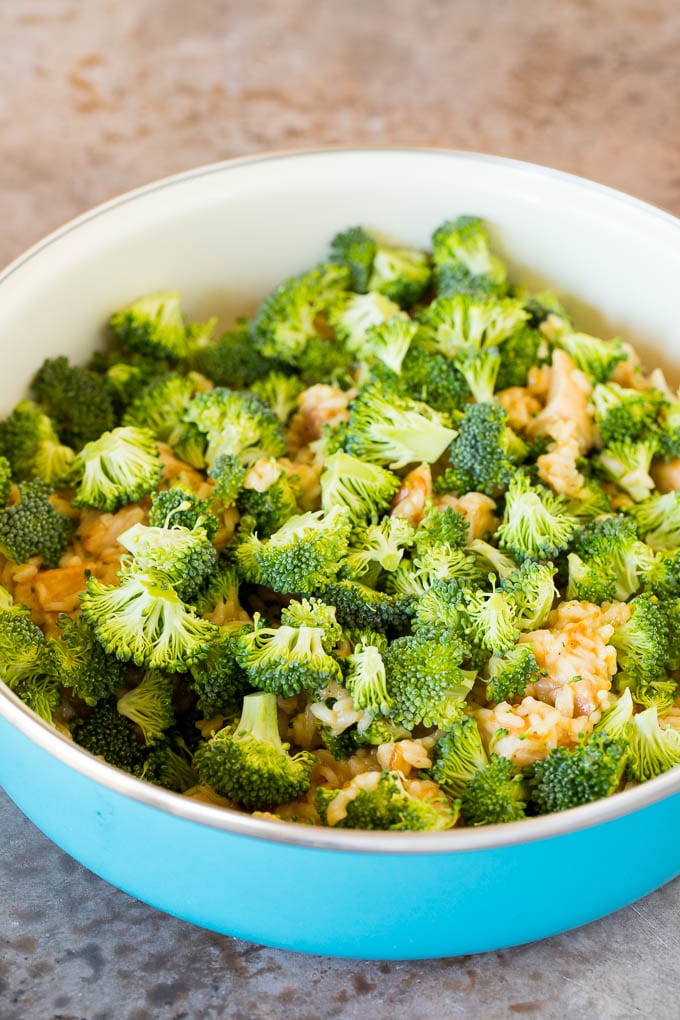 Chopped broccoli on top of chicken and rice.