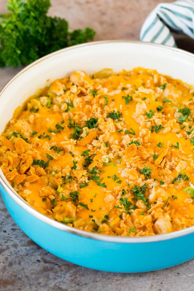 A pot of chicken broccoli casserole topped with crackers and parsley.