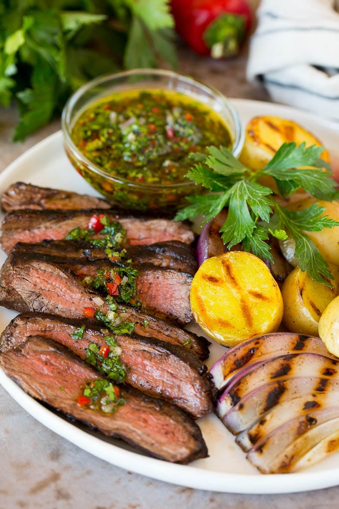 Churrasco on a plate with chimichurri sauce and grilled vegetables.