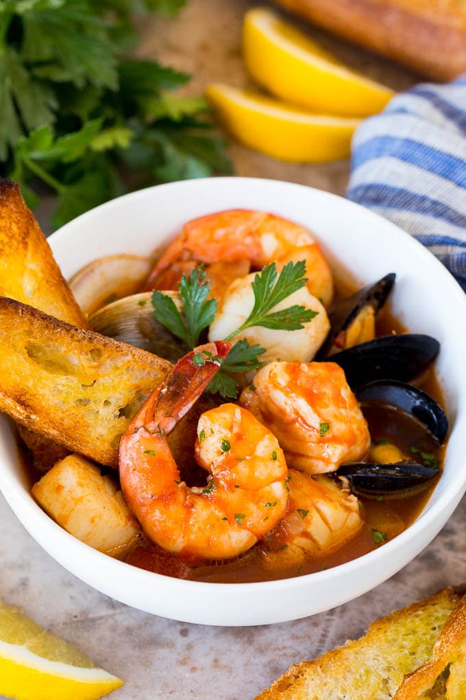 A serving bowl of cioppino with grilled bread slices in it.