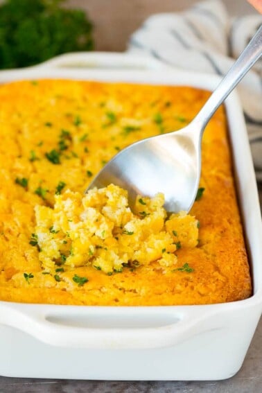 Cornbread casserole with a serving spoon in it.