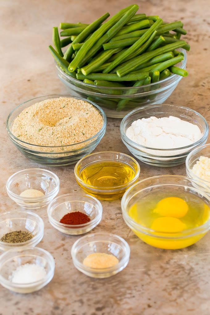 Bowls of green beans, breadcrumbs, flour, egg and seasonings.