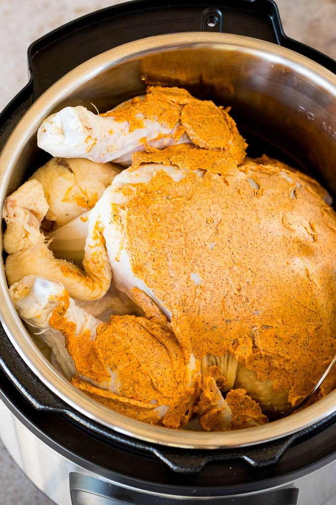 A chicken covered in flavored butter in a pressure cooker.