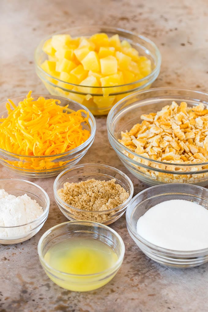 Bowls of pineapple, sugar, crackers and cheese.