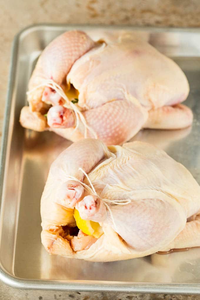 Hens on a sheet pan stuffed with lemon and herbs.