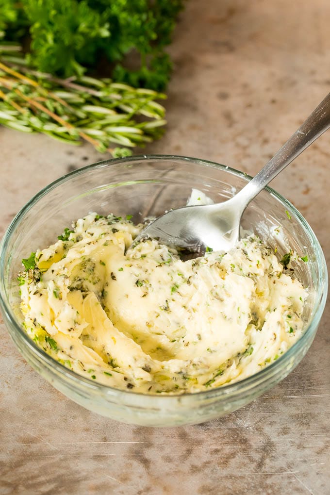 A bowl of butter mixed with garlic and herbs.