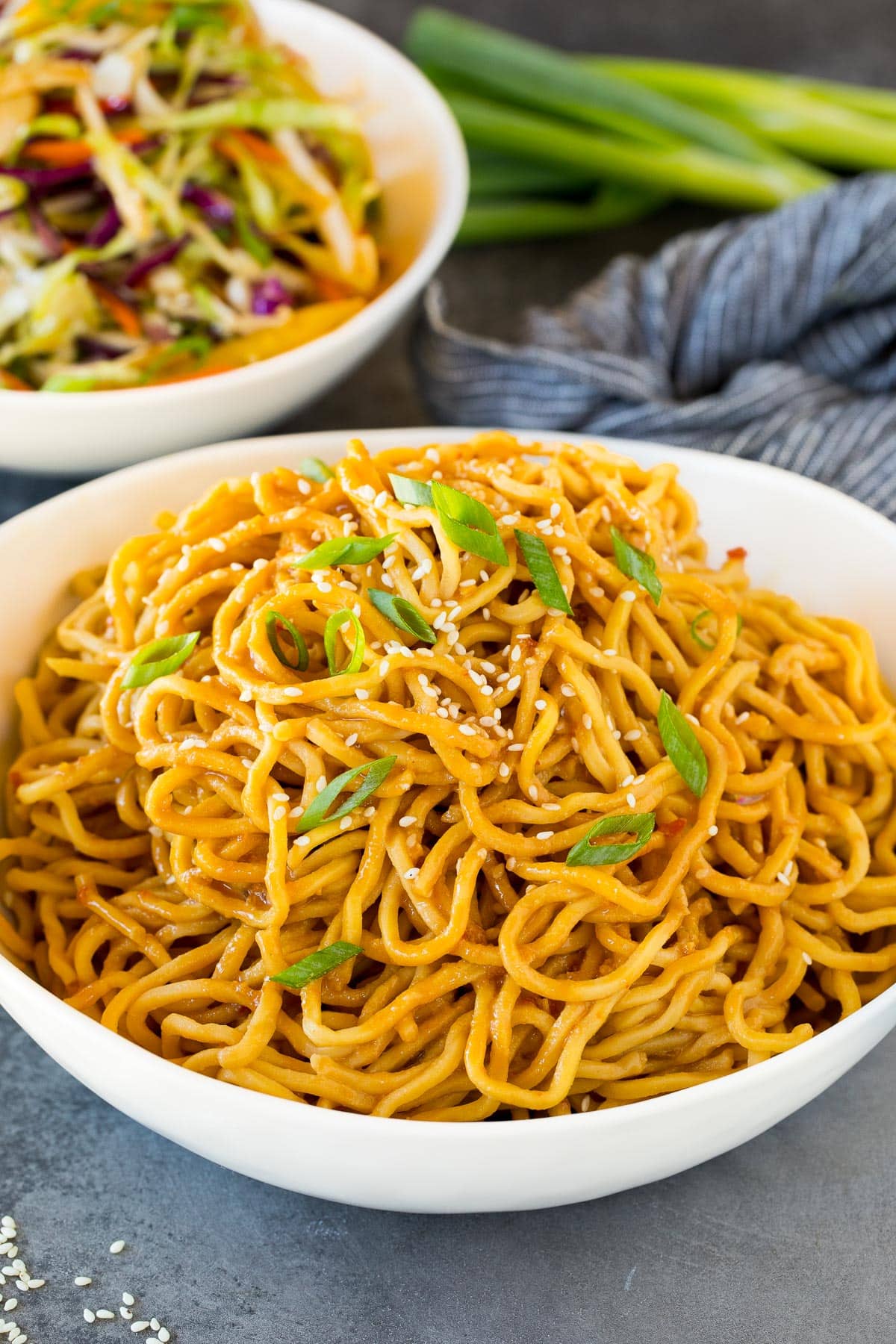 A bowl of sesame noodles topped with green onions.