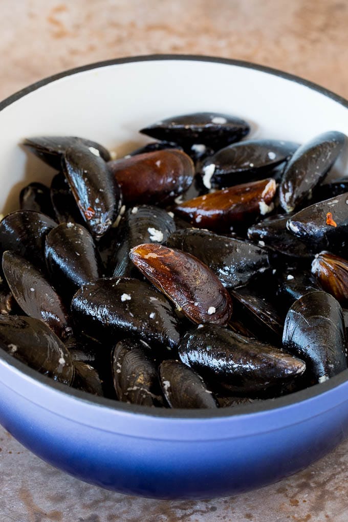 A pot of shellfish coated in butter wine and garlic.