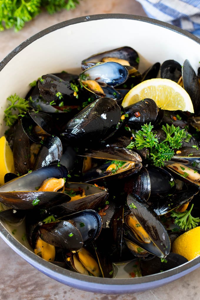 A pot of steamed mussels garnished with lemon and parsley.