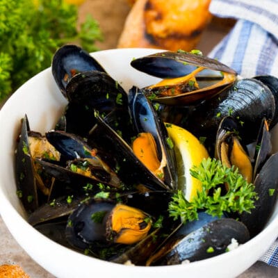 A bowl of steamed mussels served with parsley, lemon and grilled bread.