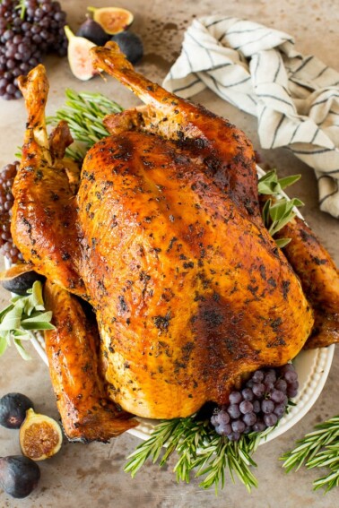 Turkey marinade over a cooked turkey, garnished with herbs and grapes.