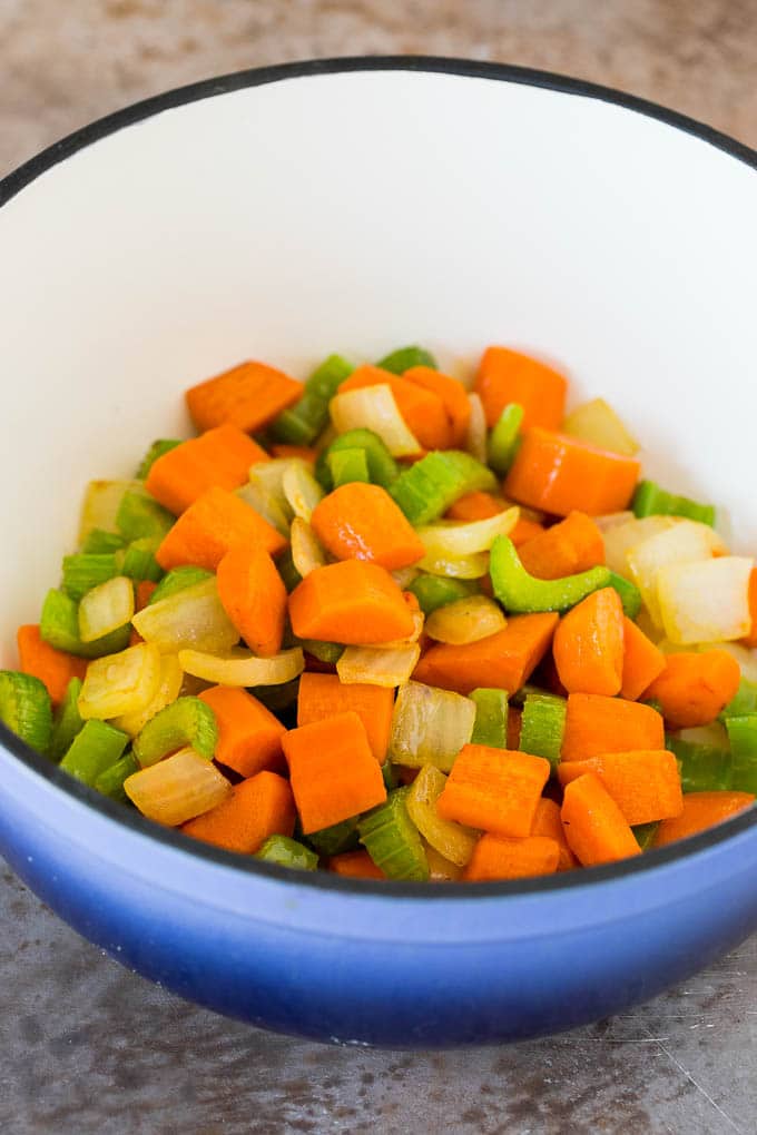 Sauteed carrots, onions and celery in a pot.