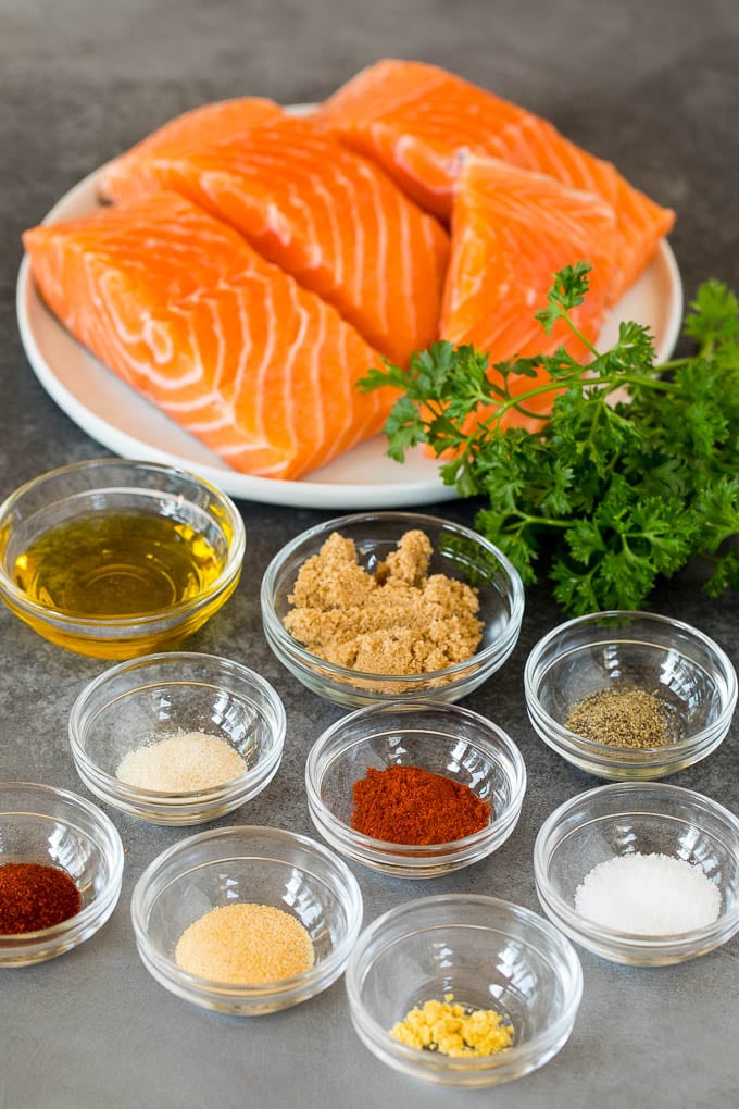 Salmon fillets and bowls of herbs, spices and olive oil.