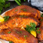 A plate of air fryer salmon fillets garnished with lemon and herbs.