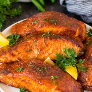 A plate of air fryer salmon fillets garnished with lemon and herbs.