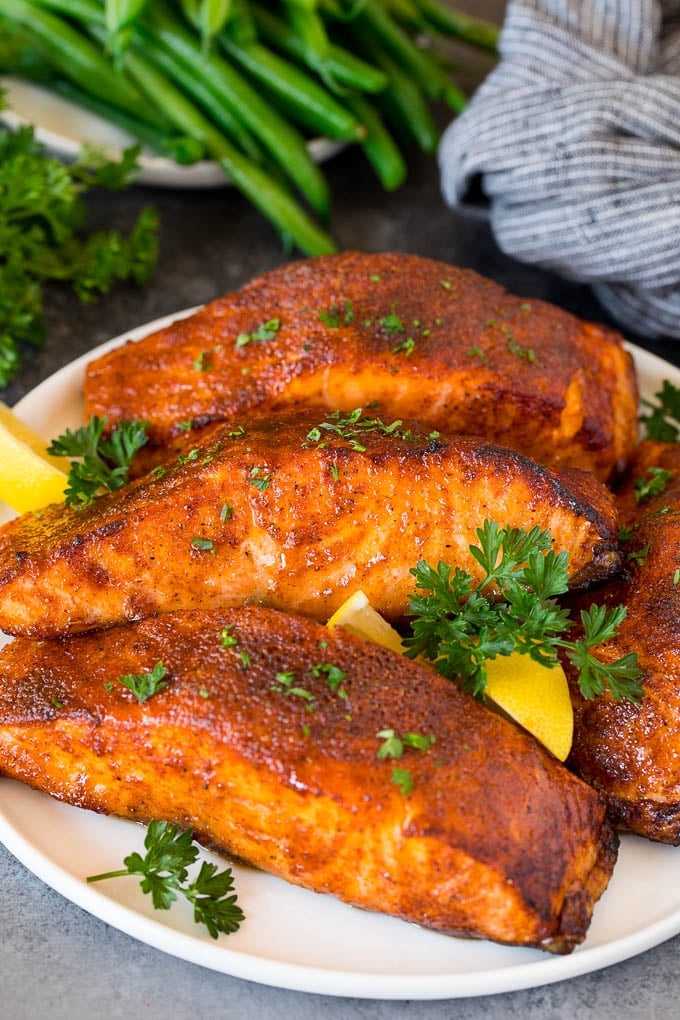 A plate of air fryer salmon fillets garnished with lemon and herbs.