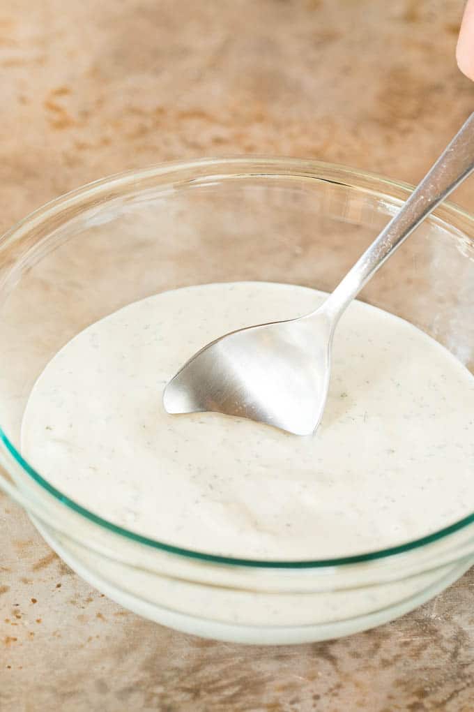 A serving spoon in a bowl of dressing.