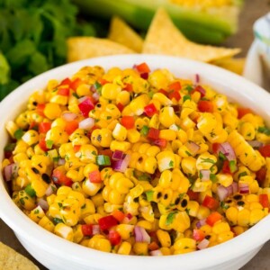 A bowl of corn salsa served with chips.