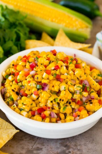 A bowl of corn salsa served with chips.