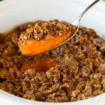 A spoon serving up a portion of crock pot sweet potato casserole.