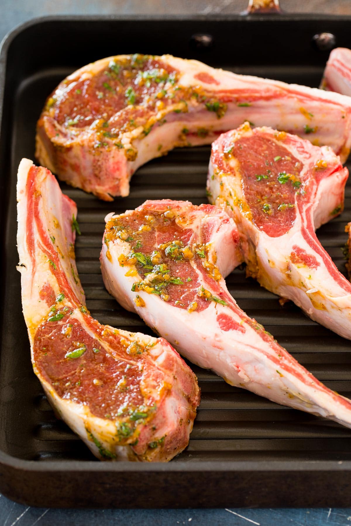 Lamb chops in marinade on a grill pan.
