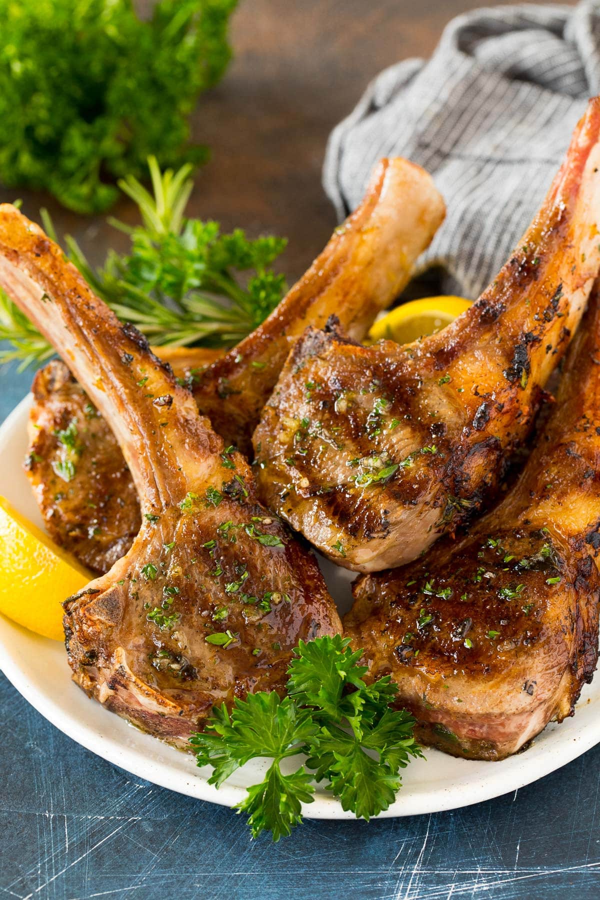 Grilled lamb chops on a plate garnished with parsley and lemon.