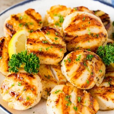 A plate of grilled scallops garnished with parsley and lemon.