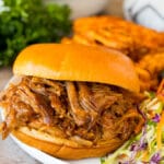 Instant Pot pulled pork on a sandwich with a side of fries and coleslaw.