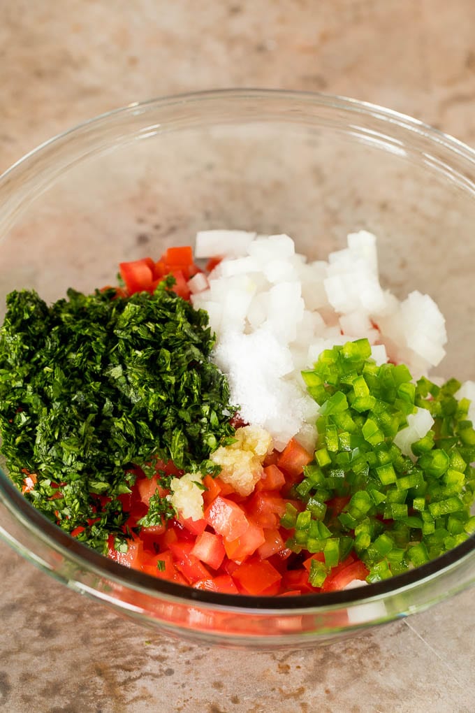 Diced tomatoes, vegetables and herbs in a bowl.