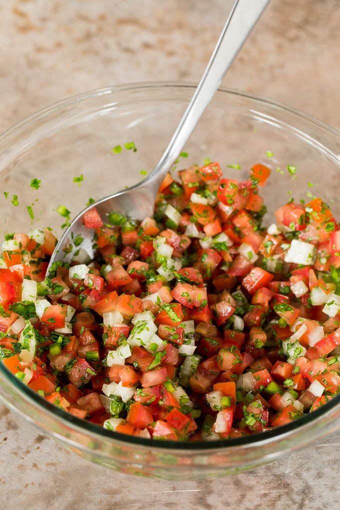 A bowl of tomatoes mixed with onions, peppers and cilantro.