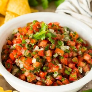 A bowl of salsa fresca served with chips.