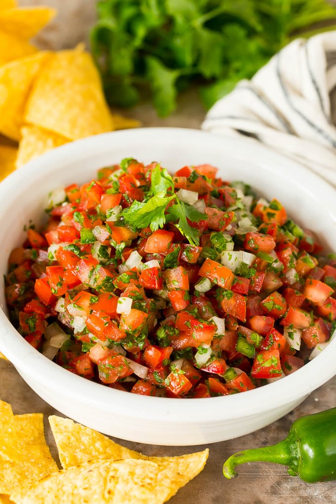 A bowl of salsa fresca served with chips.