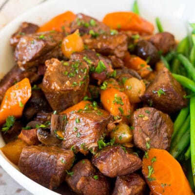 Slow cooker beef bourguignon in a bowl served with green beans.