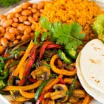A platter of vegetarian fajitas served with rice and beans.