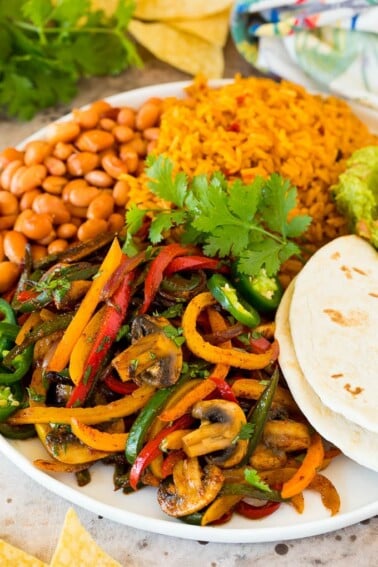 A platter of vegetarian fajitas served with rice and beans.