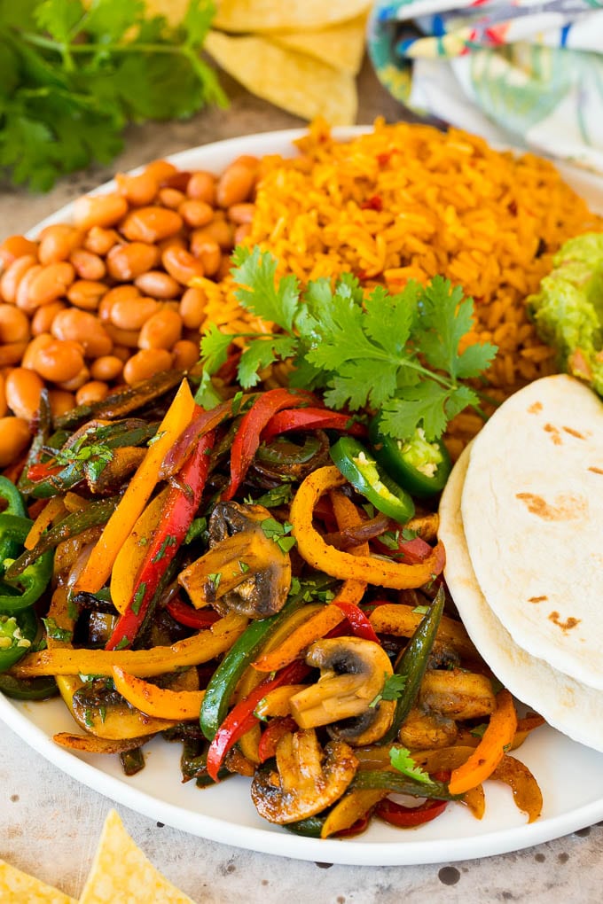 A platter of vegetarian fajitas served with rice and beans.