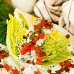 A wedge salad topped with bacon, tomatoes and cheese.