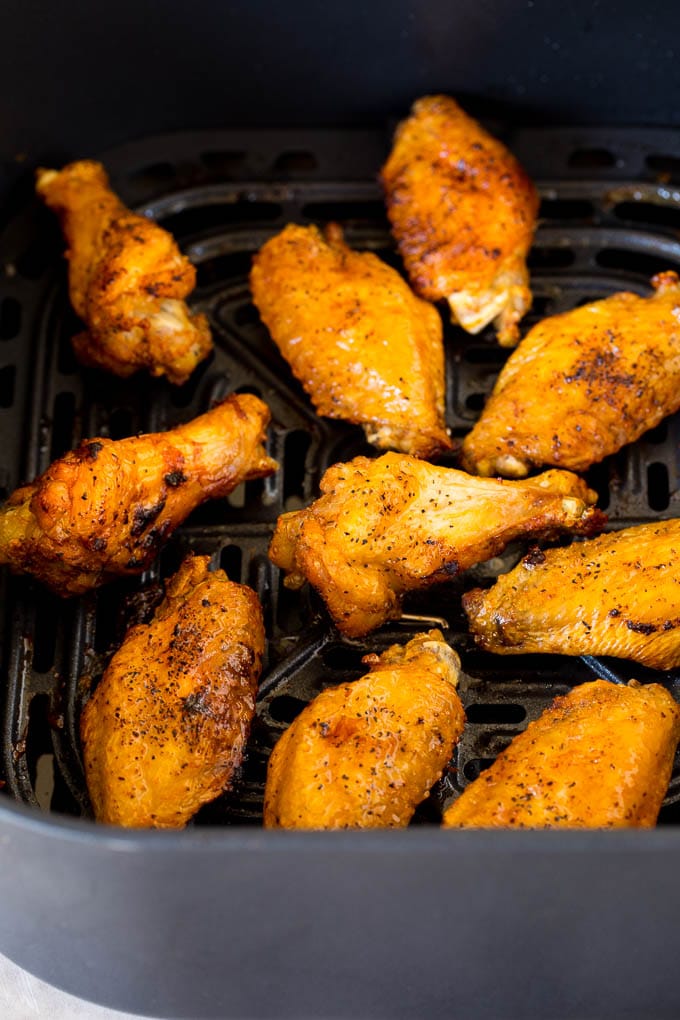 Cooked wings in the basket of an air fryer.