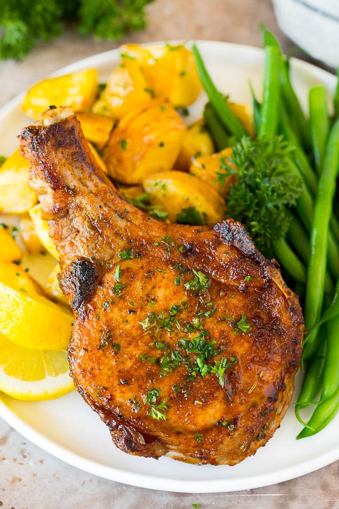 Air fryer pork chops on a plate with potatoes and green beans.