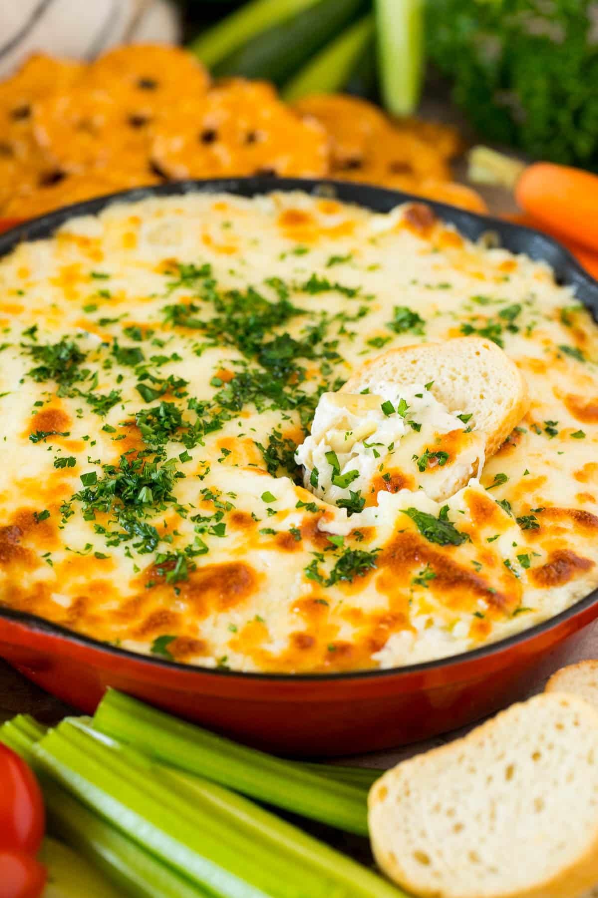 A slice of baguette in a pan full of artichoke dip.