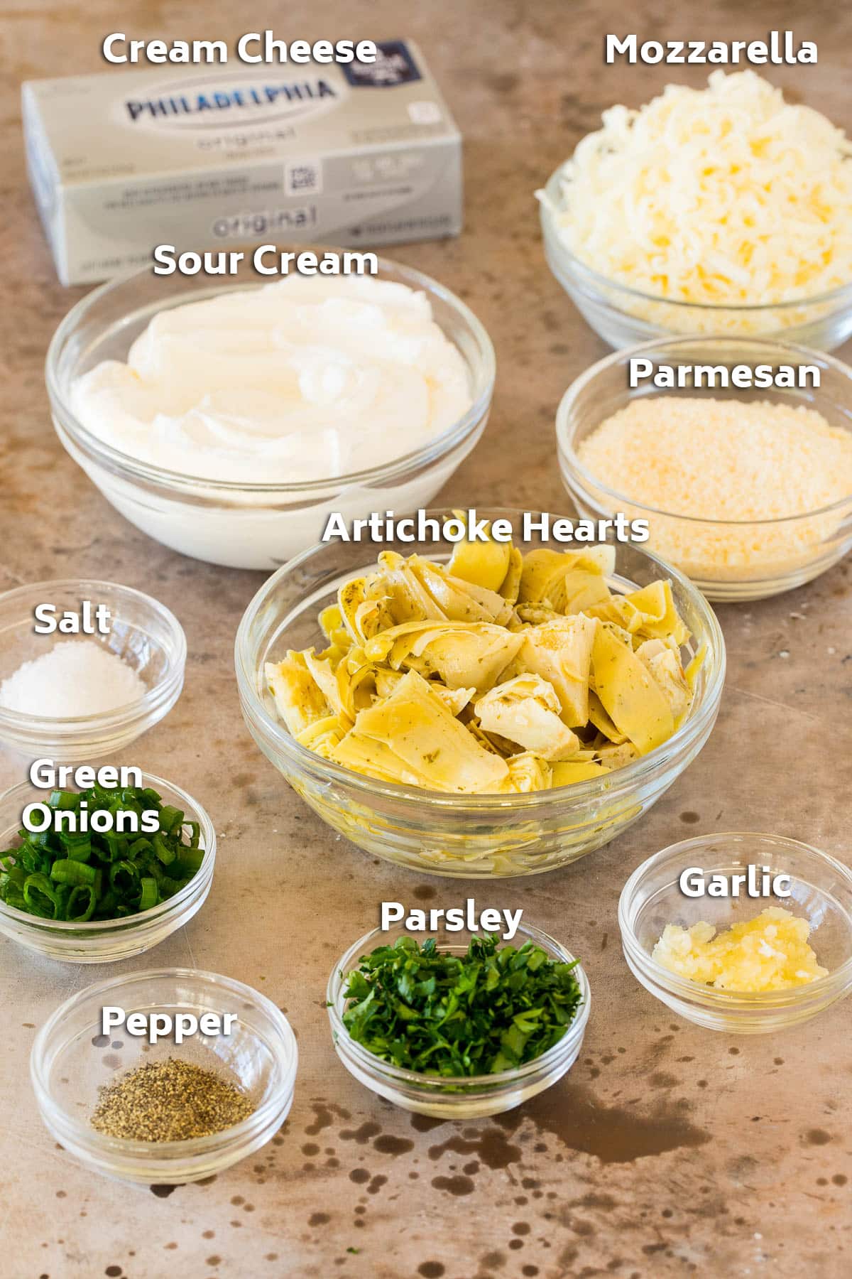 Bowls of ingredients including artichoke hearts, cheese, herbs and seasonings.