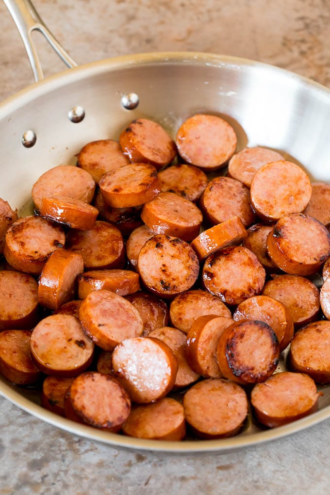 Sliced cooked kielbasa in a pan.