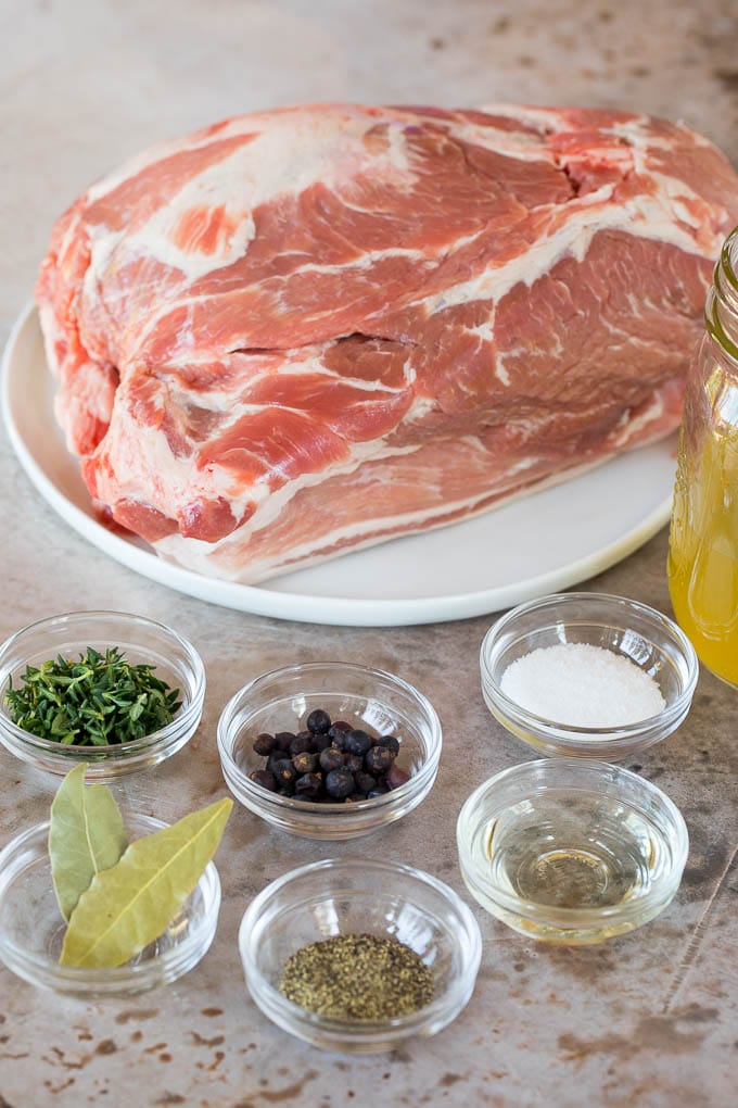 A pork roast and bowls of herbs and spices.