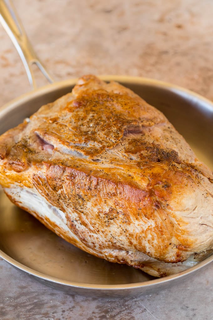 A browned pork shoulder in a pan.