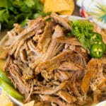 A plate of shredded Chipotle carnitas served with cilantro and chips.