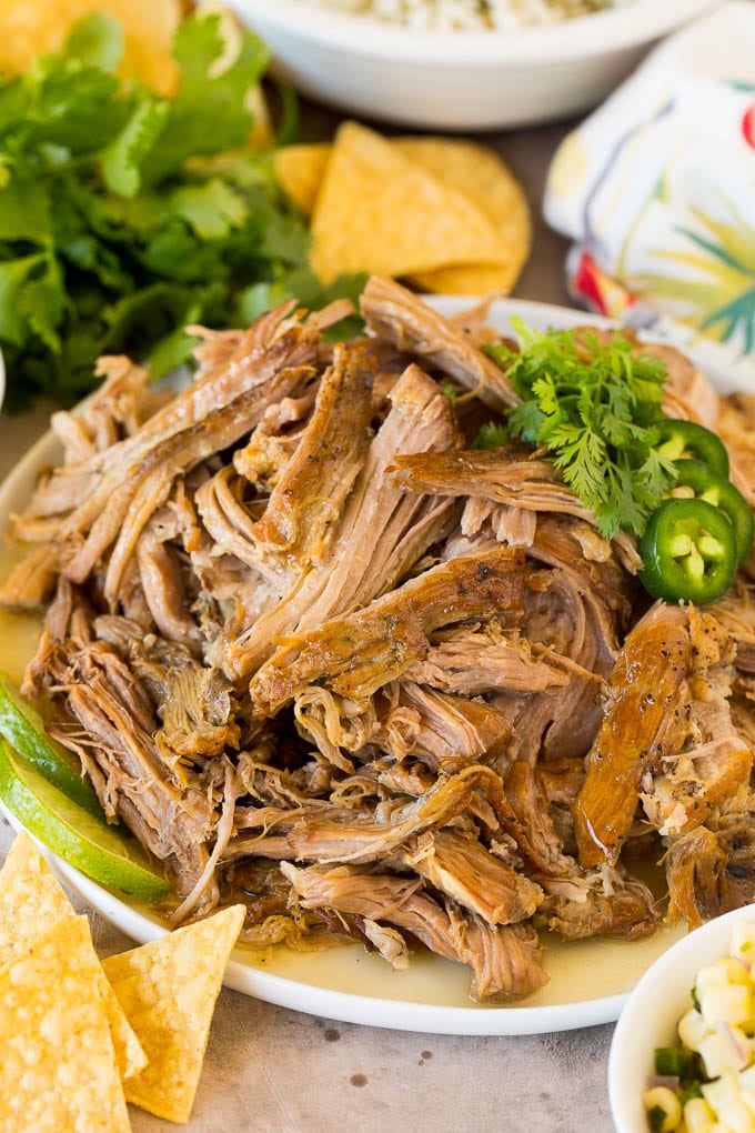 A plate of shredded Chipotle carnitas served with cilantro and chips.