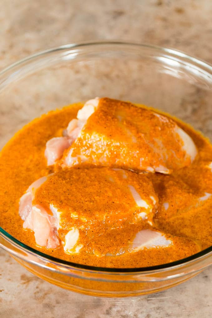 A bowl of chicken in a marinade.