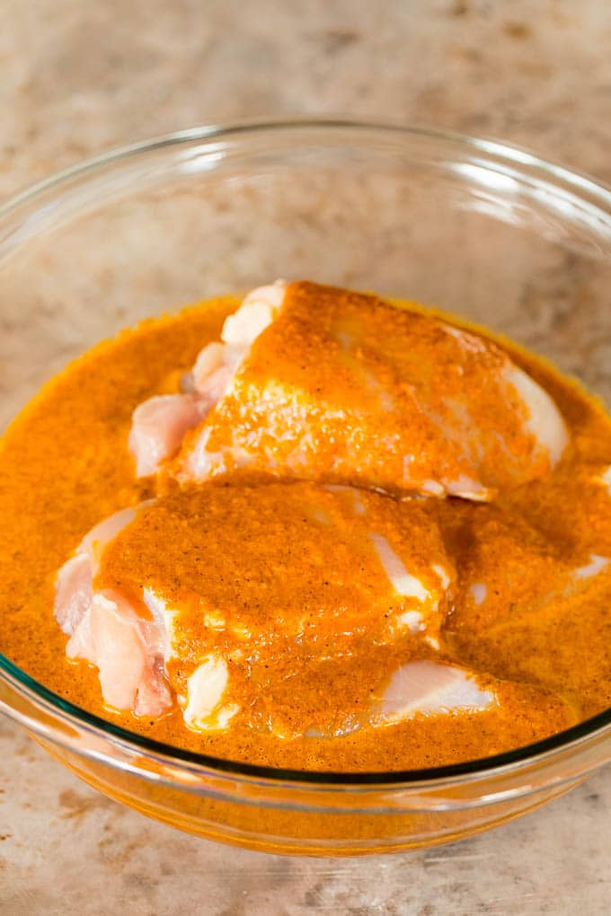 A bowl of chicken in a marinade.