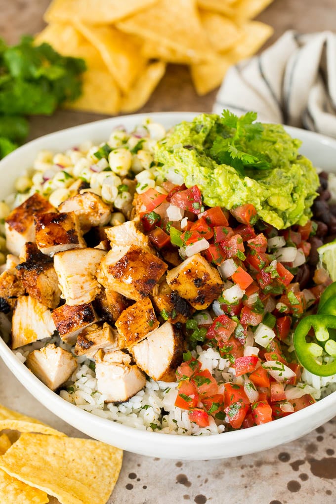 Chipotle chicken in a bowl with rice, salsa, beans and guacamole.