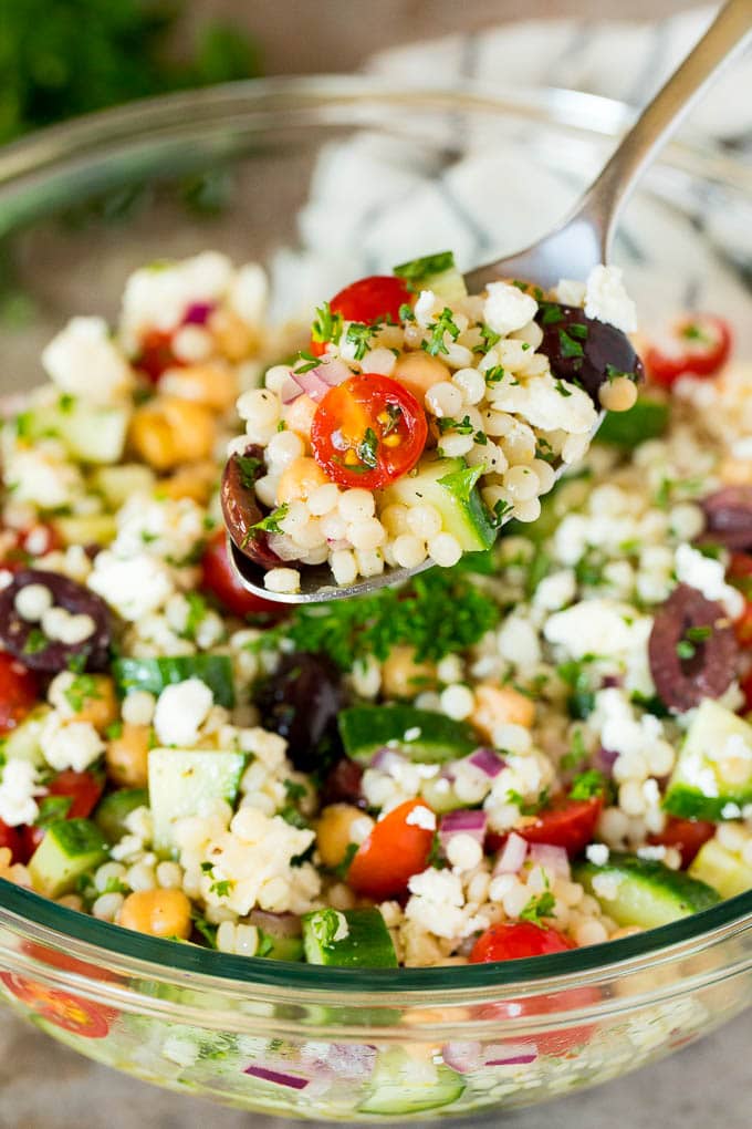 A spoon holding up a serving of couscous salad.